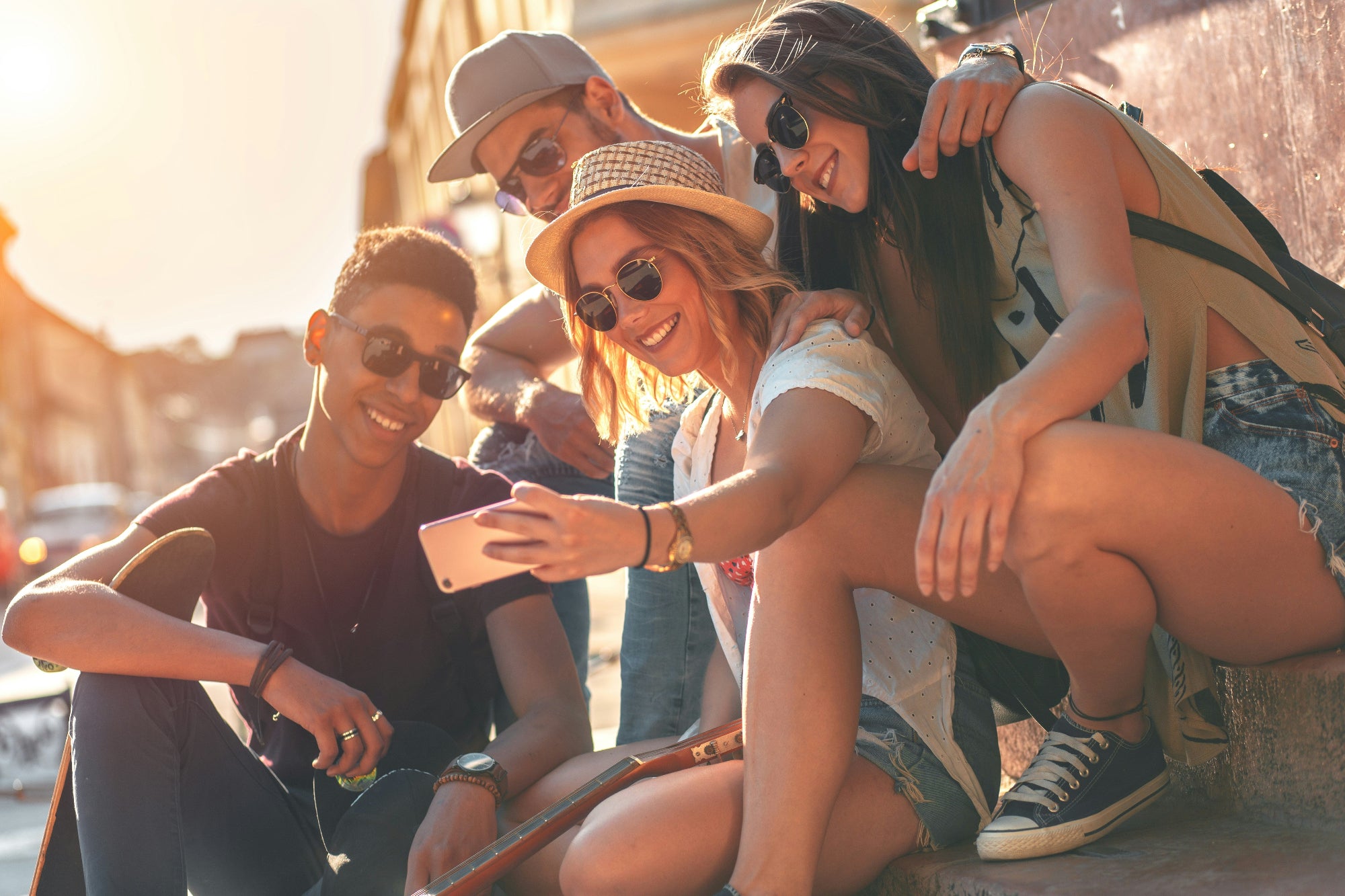 Group of friends taking a selfie outdoors with sunglasses on